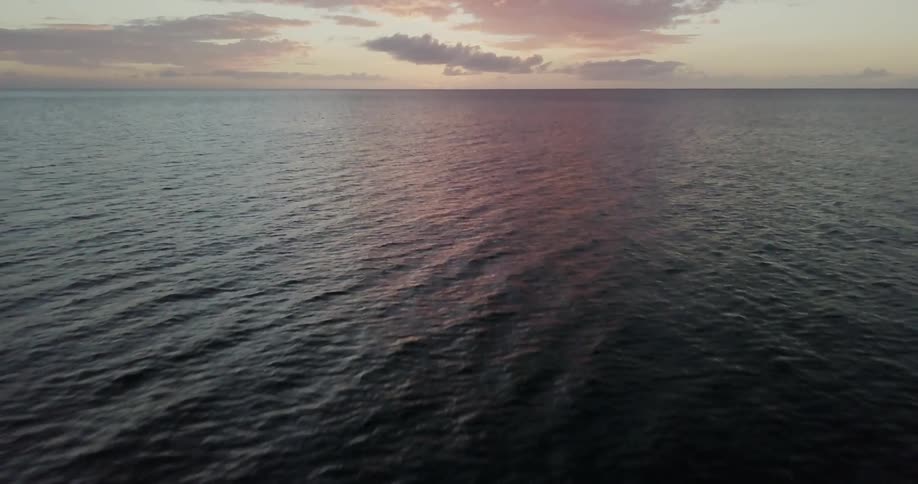 The sun is casting a pink glow over the ocean at dusk