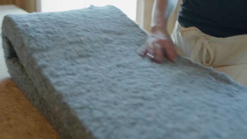 A worker lays insulation at a job site