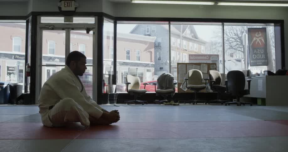 Man sits stretching in a karate dojo