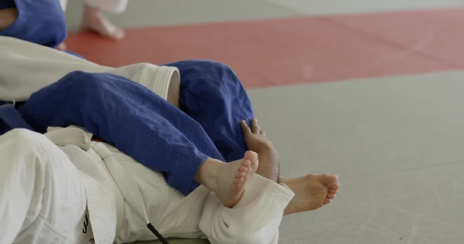 Two people practice karate on a gym mat