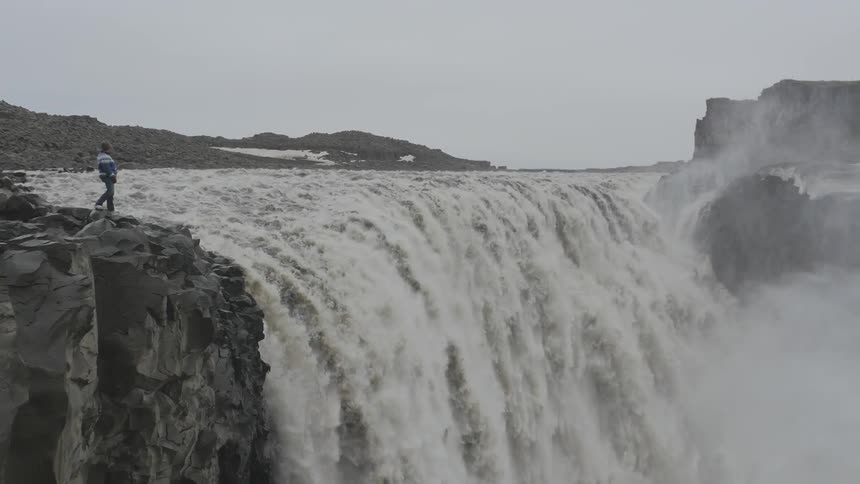 Person standing at the very top of a large waterfall