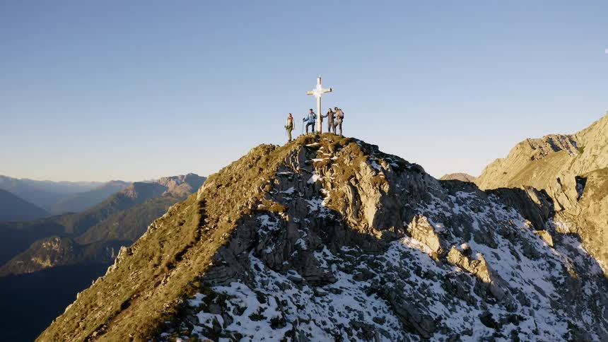 Climbers stand on a peak where a cross has been raised