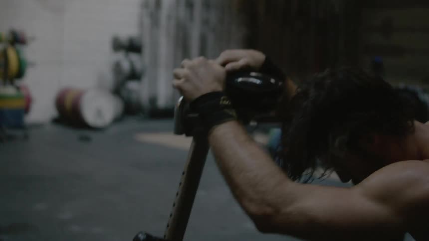 A man crouches next to a stationary bike in a gym during a workout