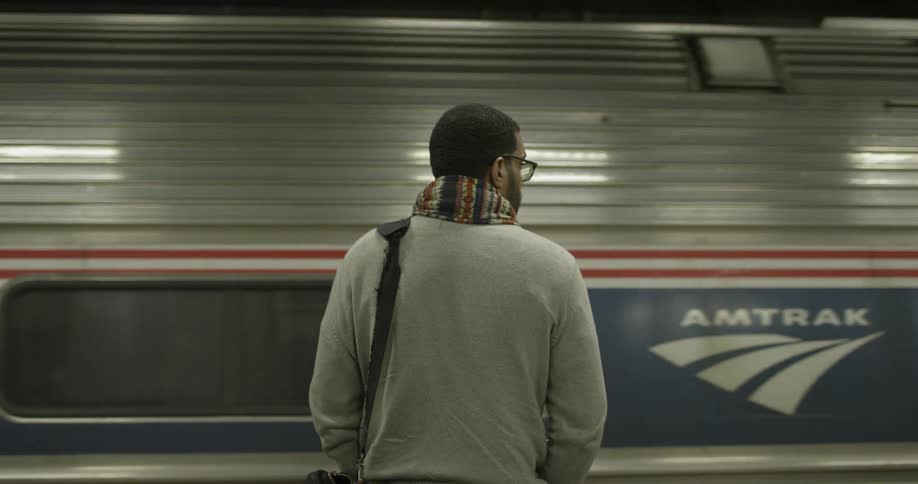 A man stands next to a moving subway train