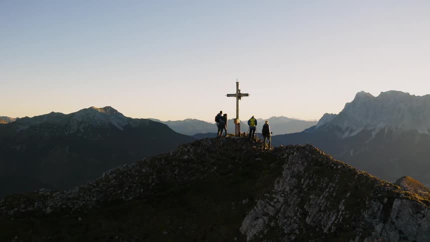 A group of people are standing on a hillside next to a cross