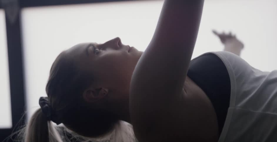 A woman is stretching and sitting up as she works out indoors during the day