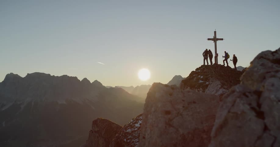 People are standing on top of a mountain next to a cross