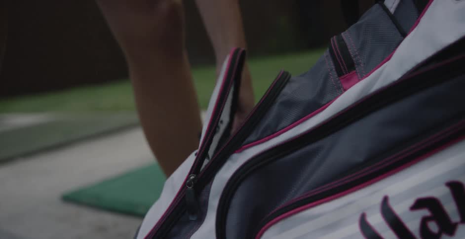 A woman zips up a golf bag