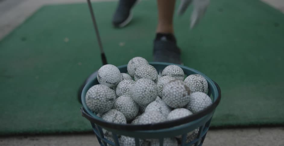 A golf ball is taken from a basket and set on a tee