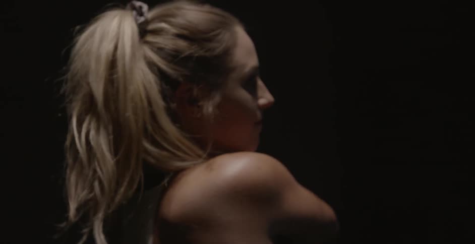 A woman swings a gold club in the dark