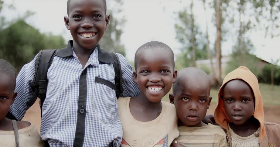 A group of kids are standing and smiling at the camera