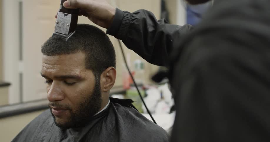 A man is having his head shaved in a barber shop