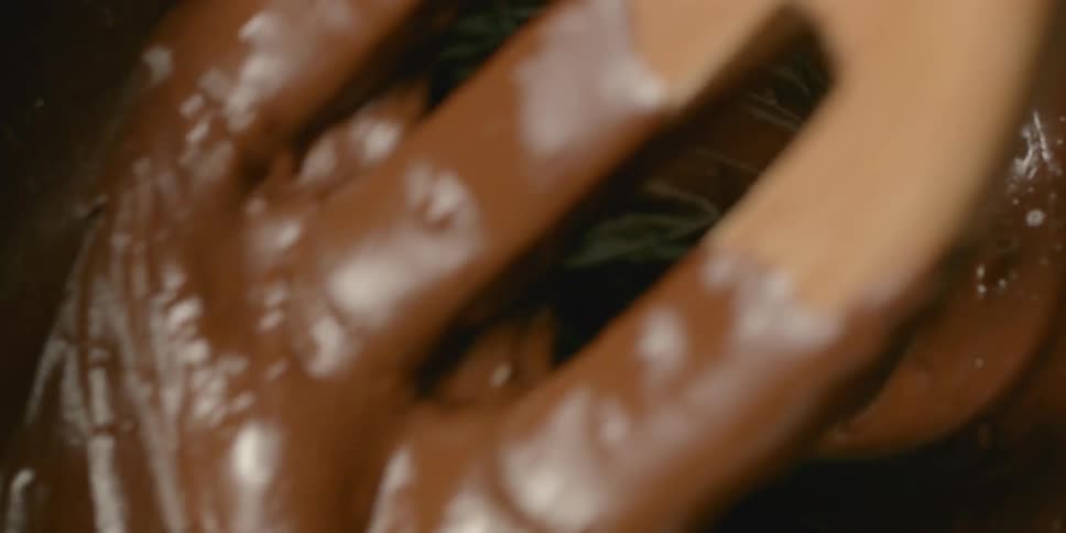Chocolate batter is stirred with a wooden spoon