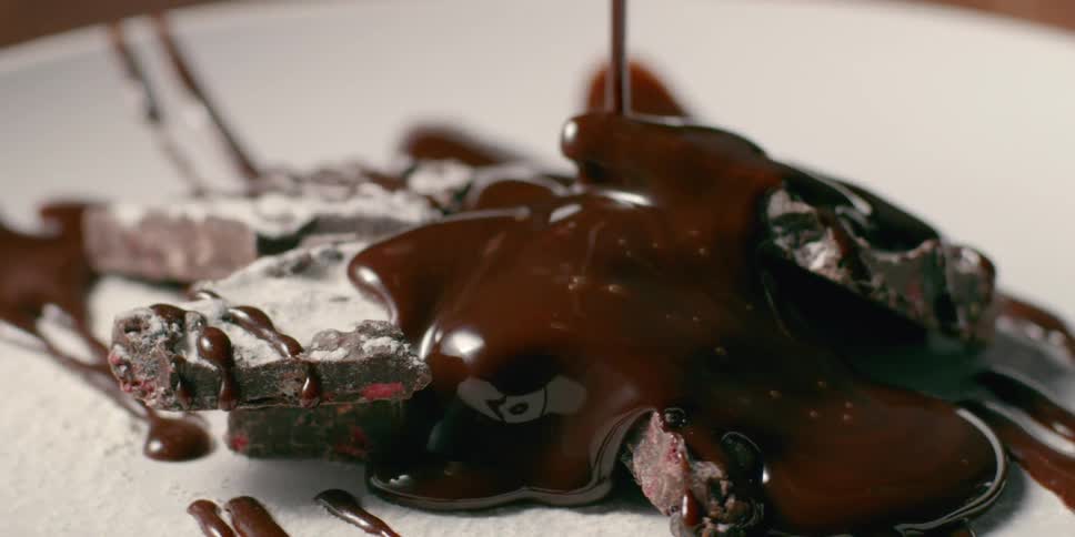 Chocolate sauce is poured onto plated dessert