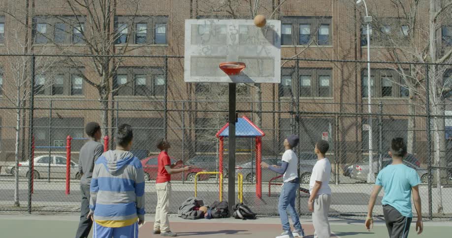 Boys play basketball on an outdoor court