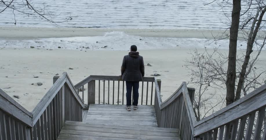 A man looks at a lake on a chilly day