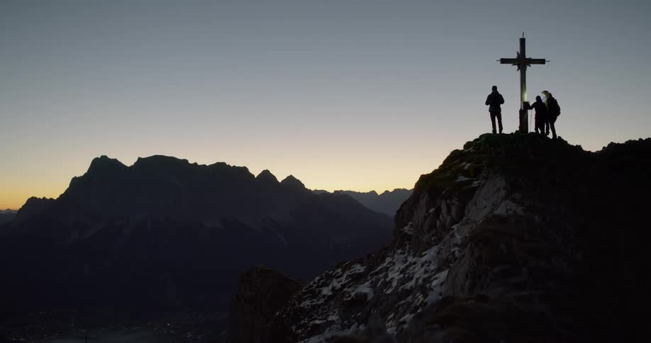 People are standing on top of a hill next to a cross