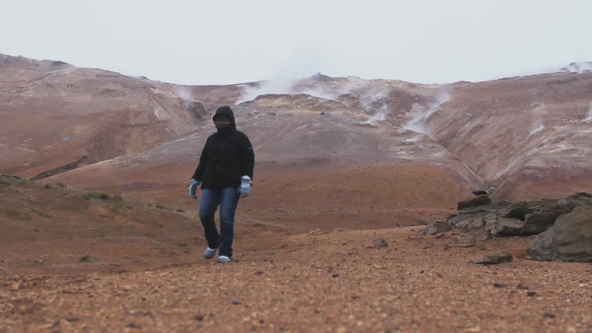 A person hikes through a mountain canyon on an overcast day