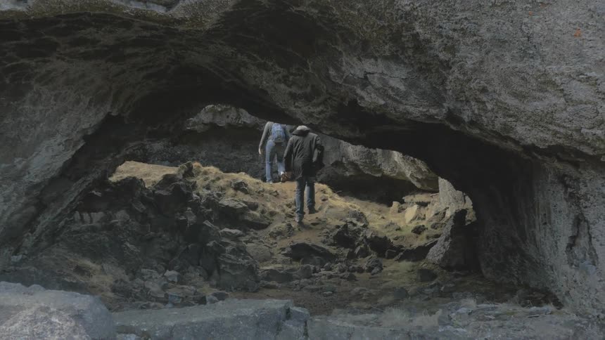People walking under a large rock formation
