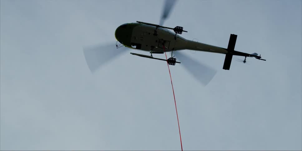 A helicopter has a rope attached and is hovering