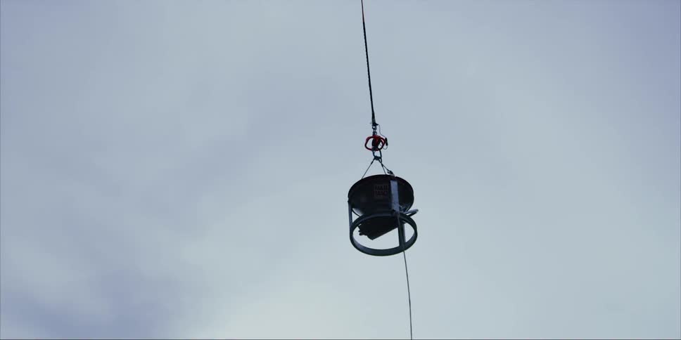 Equipment hangs from a hovering helicopter