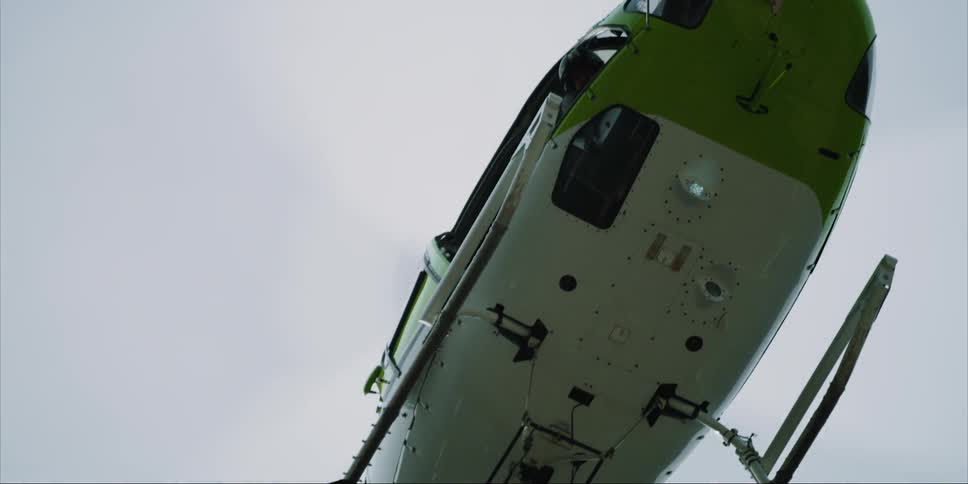 A helicopter pilot look down at a cable while he flies
