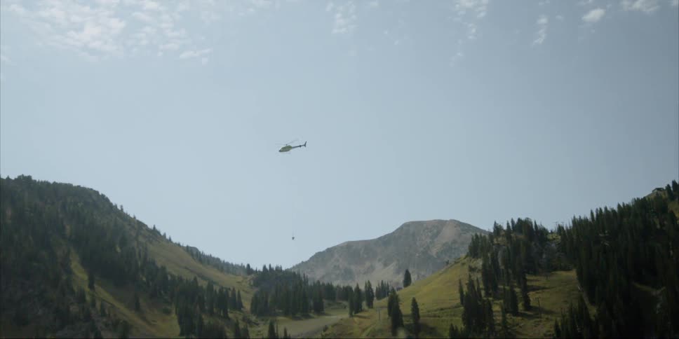 A helicopter flies over mountains