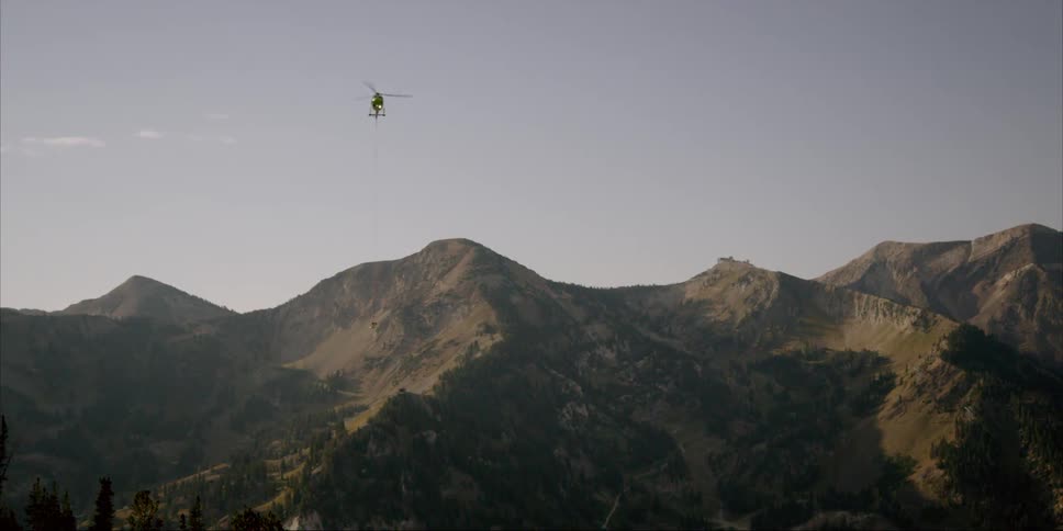 The helicopter flies high over the mountain ahead