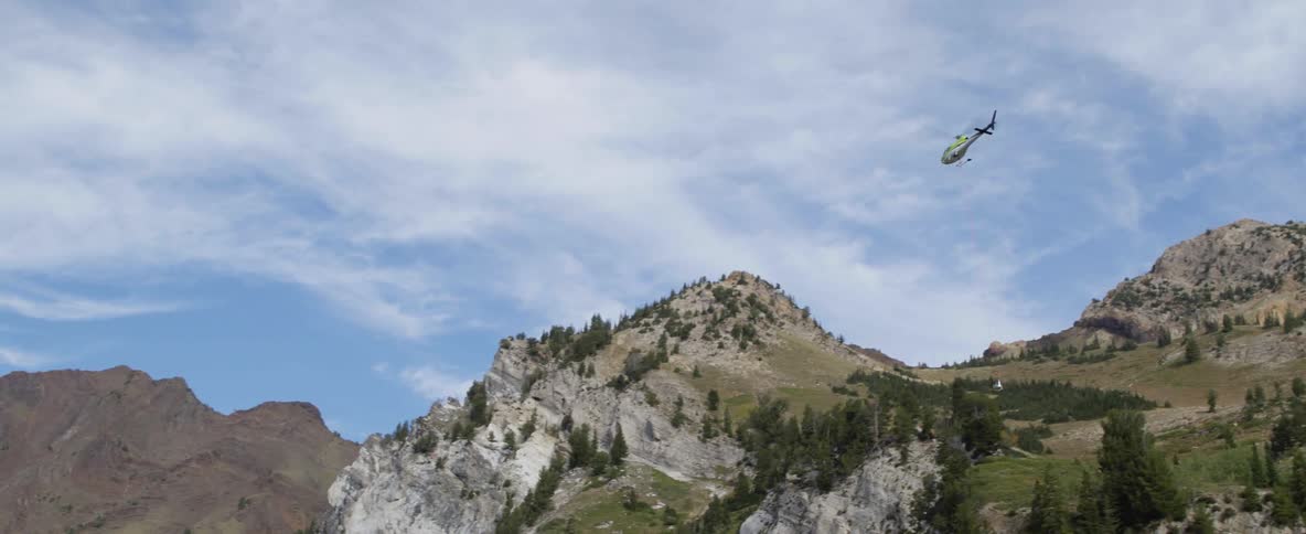 A helicopter flies over mountains