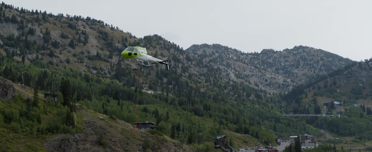 Helicopter flying over a road and mountains