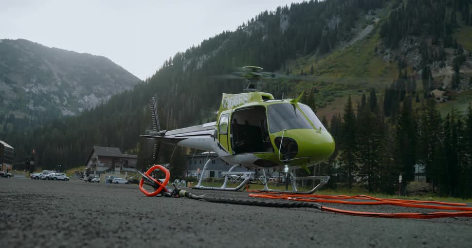 A helicopter sits in a parking lot in mountains