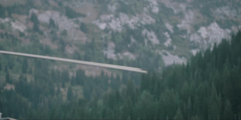 The blades of a helicopter are starting to spin faster as it sits outside in daylight