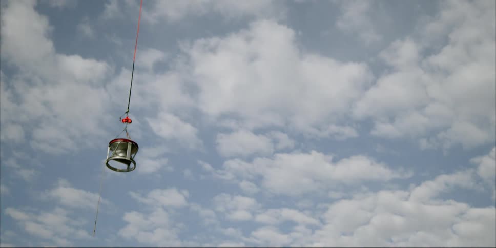The helicopter pulls the metal bin low to the ground