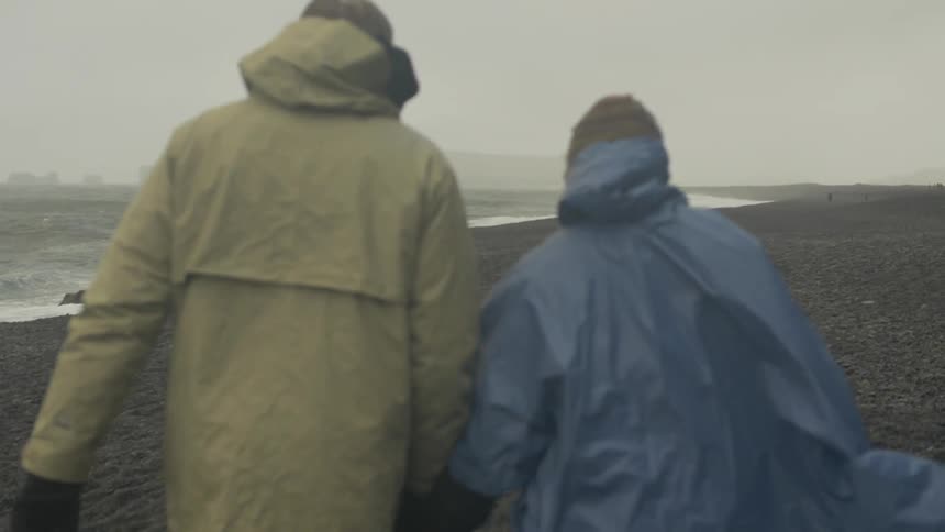 Two people walking on the beach on a foggy day