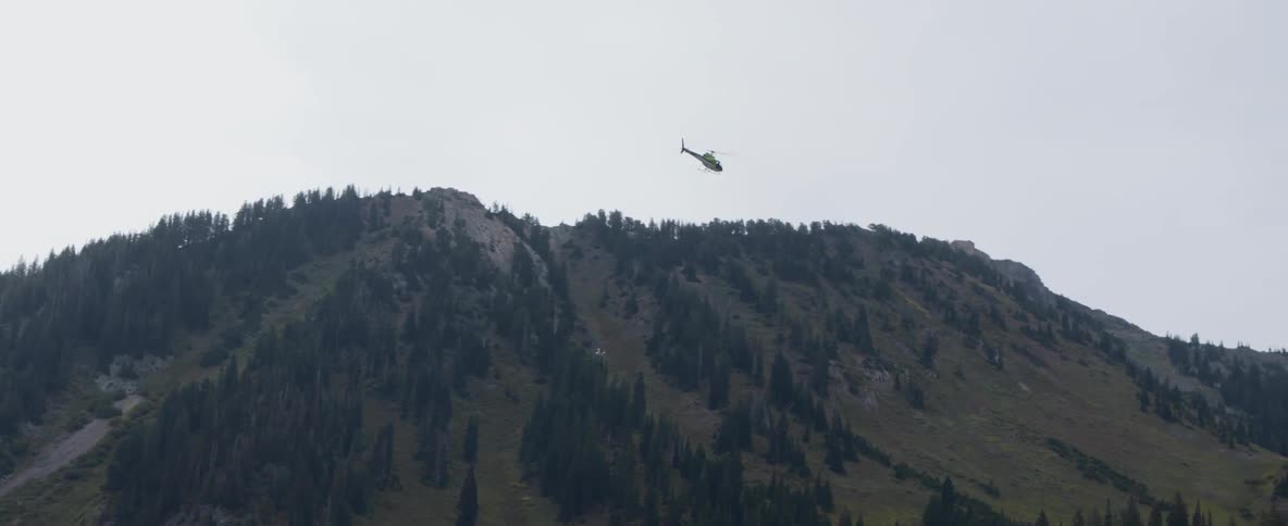 A helicopter carries equipment over mountains