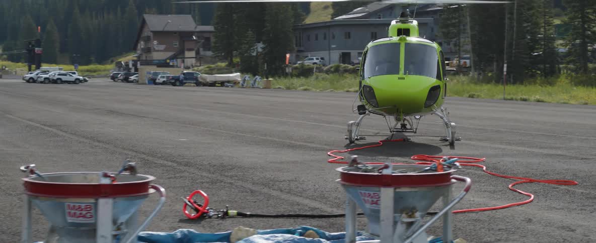 A helicopter sits in a parking lot in the mountains