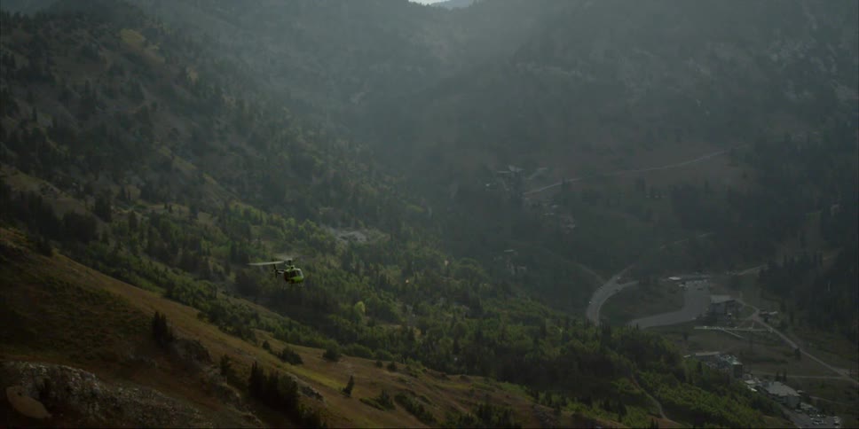 A helicopter flies in a mountain valley