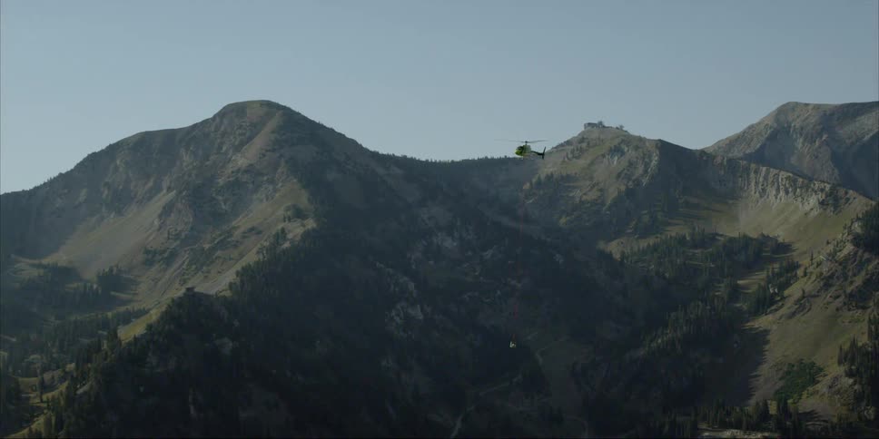 A helicopter carries equipment over mountains