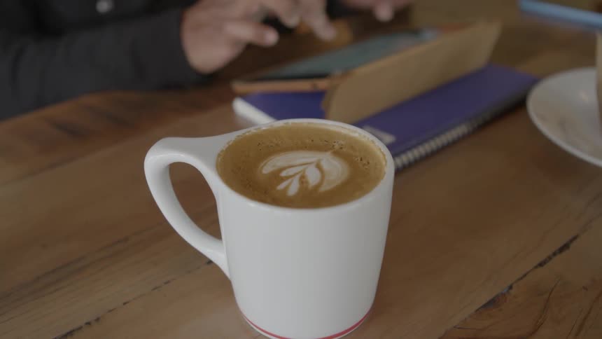 Person types on a tablet with a mug filled next to it