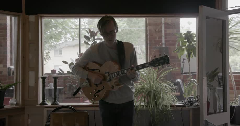 Man stands in studio playing electric guitar