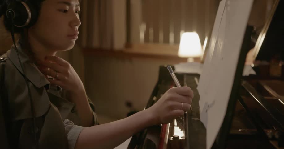 Pianist sits in recording studio and makes notes on sheet music