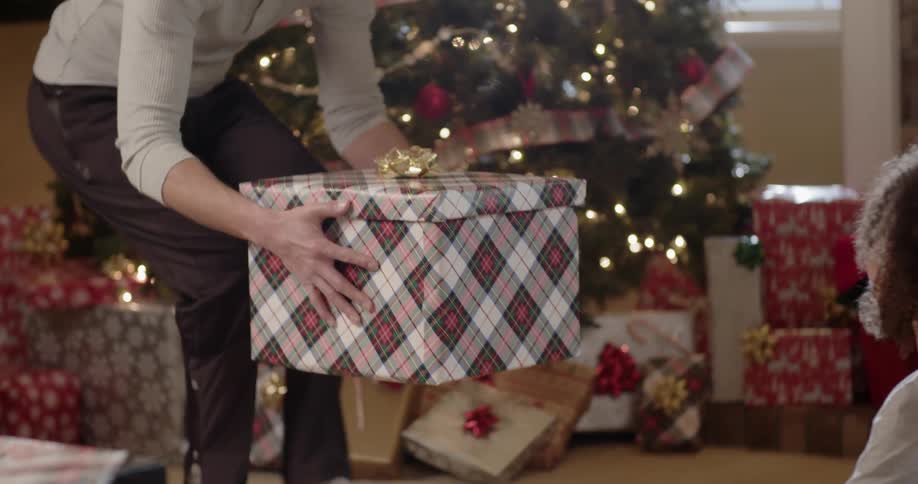People sit around a christmas tree and open presents