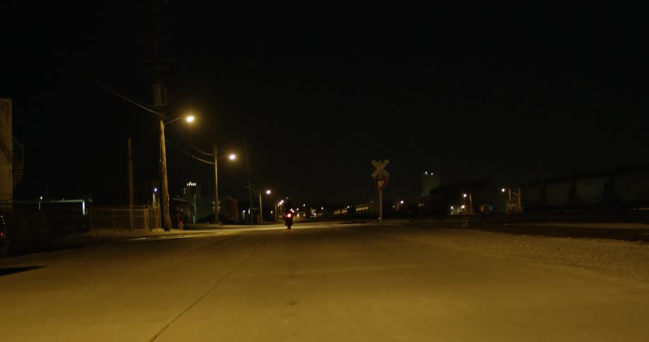 A person rides a motorcycle down a street at night