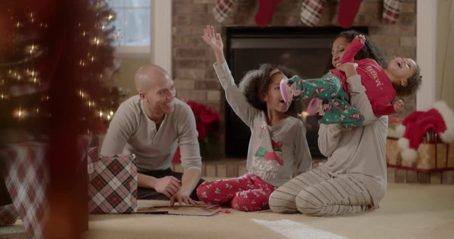 A family smiles next to a christmas tree