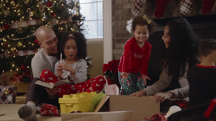 People sit around a christmas tree and open presents