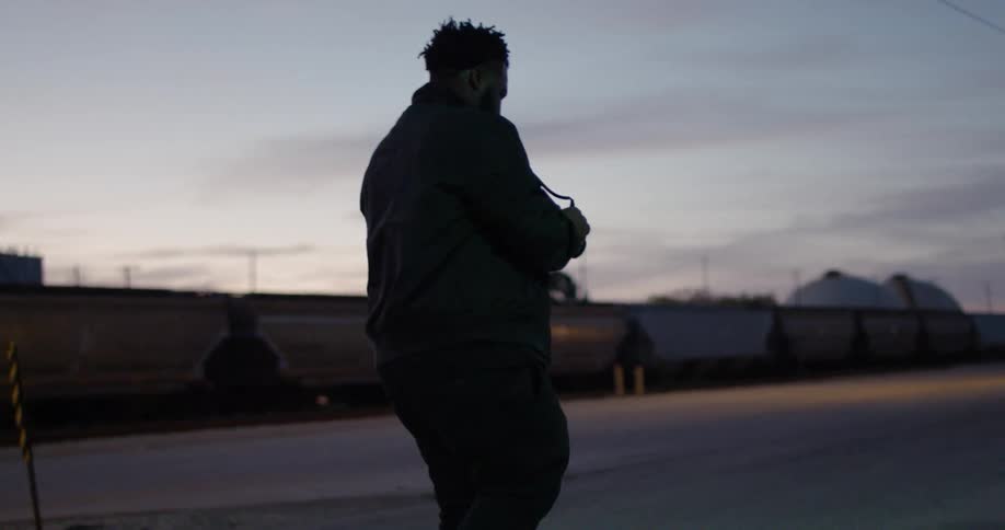 A man walks near a parked train at sunset