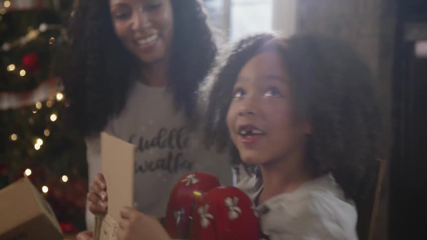 A young girl plays in a box next to a christmas tree