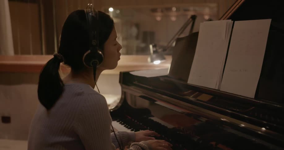 A woman is playing the piano while wearing headphones