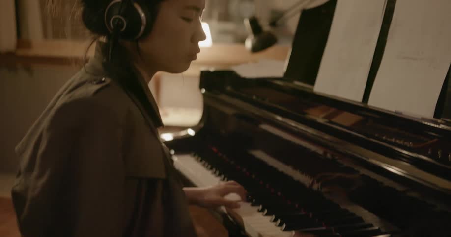 A woman is playing a piano in a music recording studio