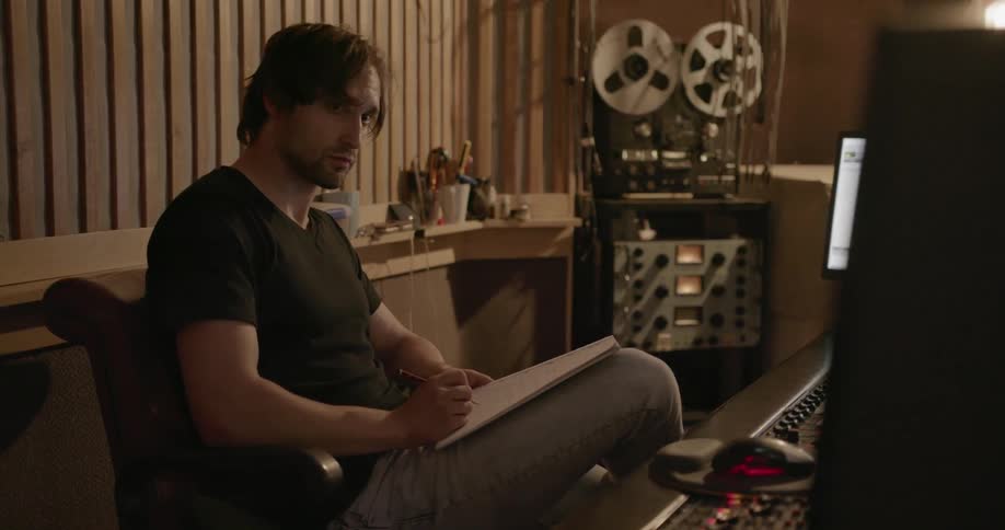 A man sits down at a mixing station in a music studio